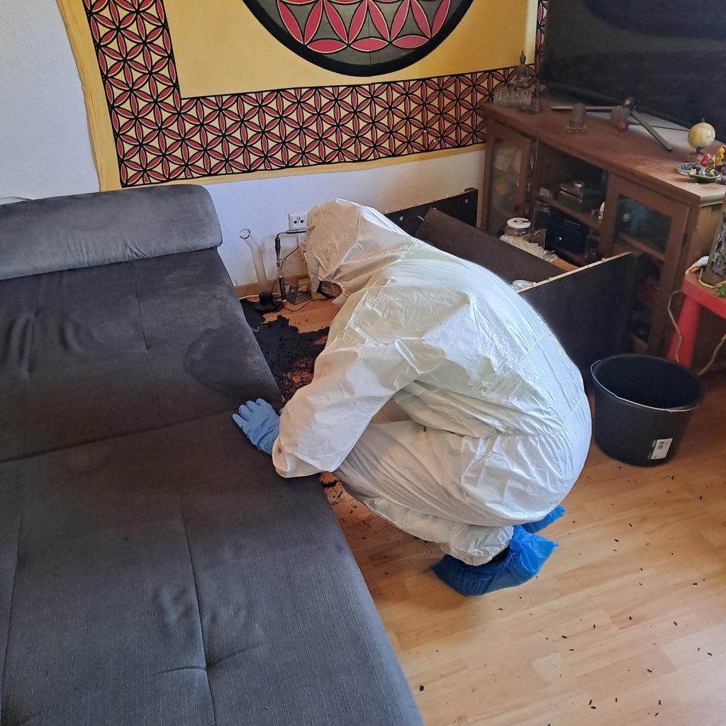 Ein Mann reinigt den Boden in einem Schutzanzug.
