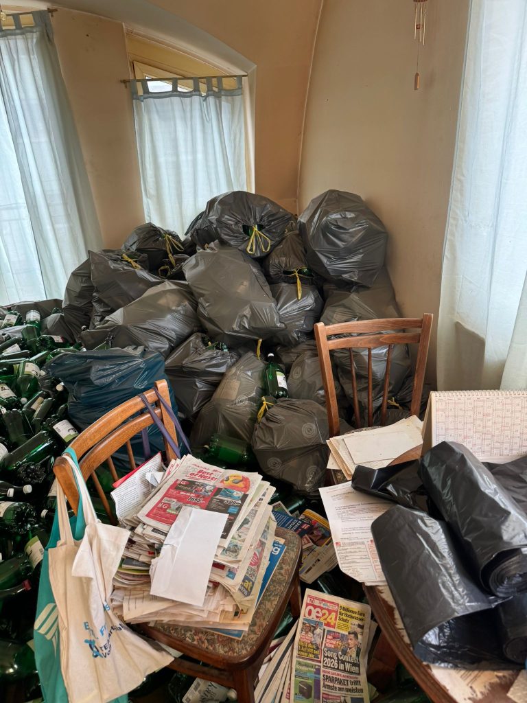Ein Zimmer voller Flaschenmüll, darunter auch Zeitungen.
