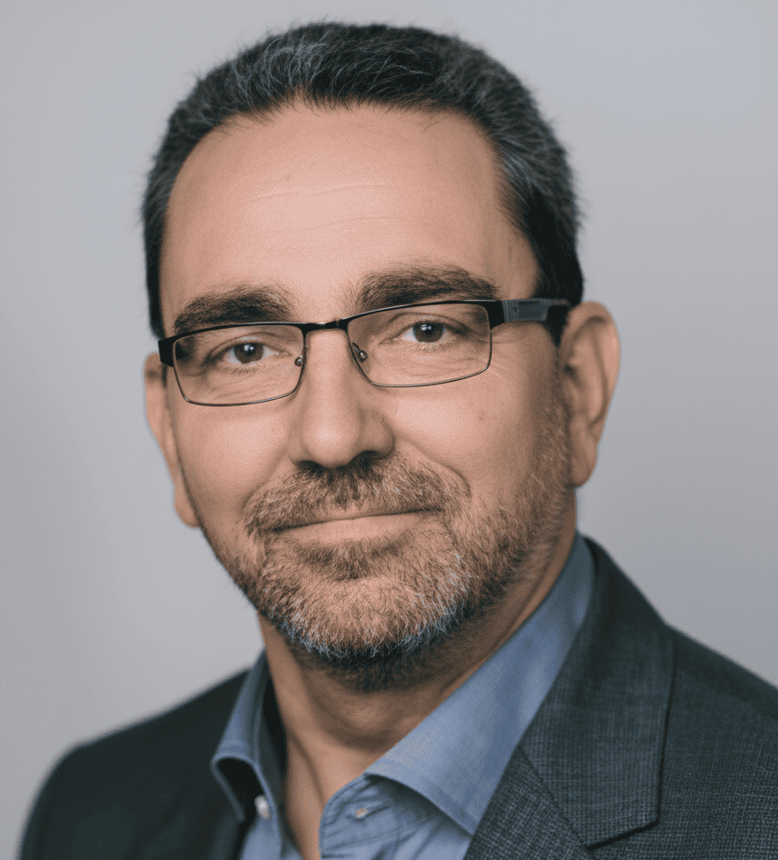 Ein Mann mit Brille und Anzugjacke schaut in die Kamera.